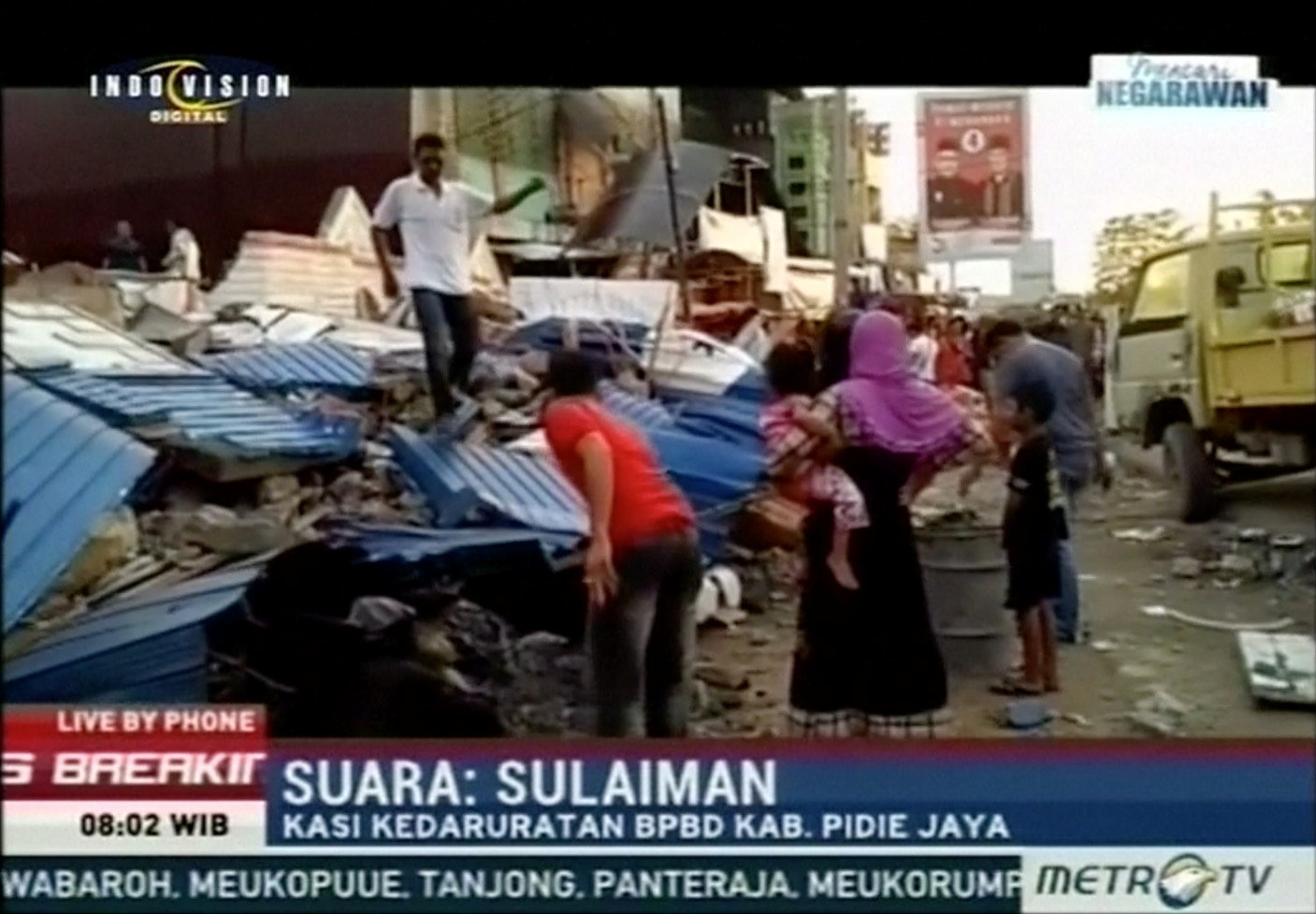 People stand next to rubble of collapsed buildings following an earthquake in Pidie Jaya, Aceh, Indonesia in this still frame taken from video December 7, 2016. METRO TV/Via REUTERS TV