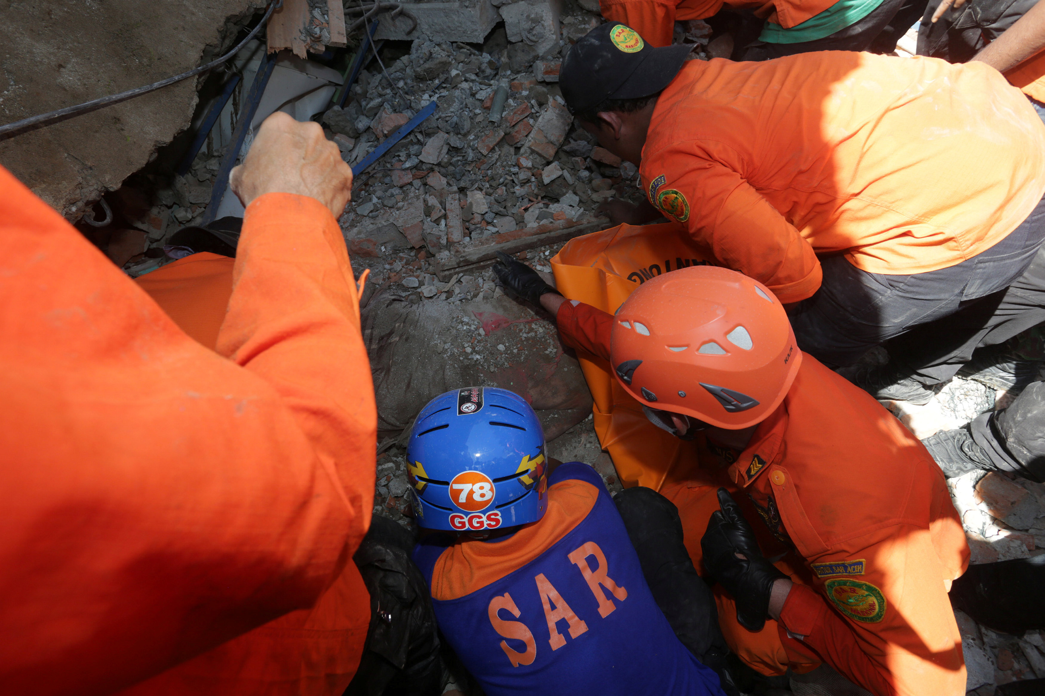 Rescue workers try to remove a victim from a collapsed building following an earthquake in Lueng Putu, Pidie Jaya in the northern province of Aceh, Indonesia December 7, 2016 in this photo taken by Antara Foto.  Antara Foto/Irwansyah Putra/via REUTERS