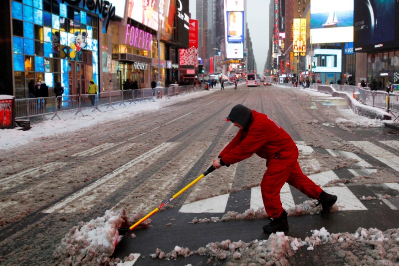 A worker clears the snow from the crosswalk in Times Square, Manhattan, New York City, U.S. December 17, 2016.  REUTERS/Andrew Kelly