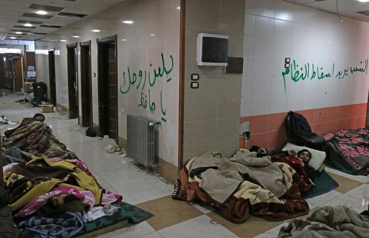 Injured and sick people wait inside a hospital to be evacuated from a rebel-held sector of eastern Aleppo, Syria December 17, 2016. The arabic on the wall reads: 'The people want to bring down the regime' (R) and 'Curse your soul, oh Hafez' (L). REUTERS/Abdalrhman Ismail