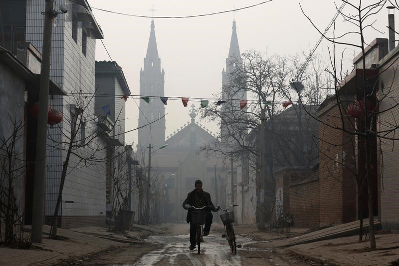 A man cycles down a road in front of the Sacred Heart of Jesus Church in Wuqiu village, Hebei Province, China, December 11, 2016. Picture taken December 11, 2016. REUTERS/Thomas Peter