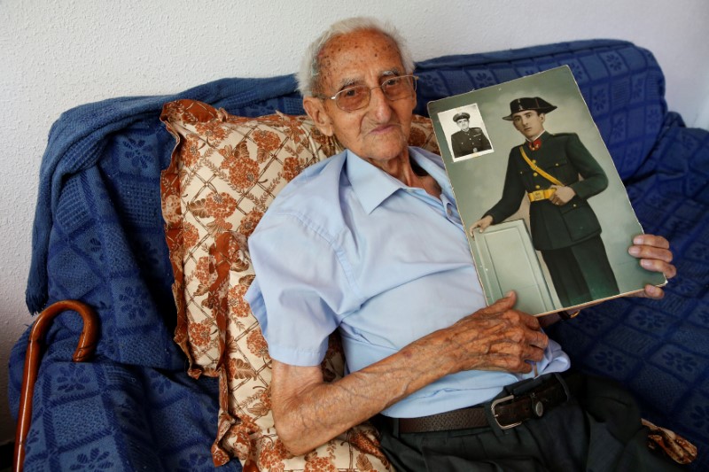 Gumersindo Cubo, 101, poses for a portrait with a picture of himself when he was young, in his home in Casavieja, Avila, near Madrid, Spain, July 12, 2016. Cubo puts his longevity down to a childhood spent in a house in the woods with his eight brothers and sisters, where his father was a park ranger. "It's from inhaling the pine resin from the woods where I lived as a child," he says, telling of how his mother would put a jar of the resin under the bed of the sick. REUTERS/Andrea Comas