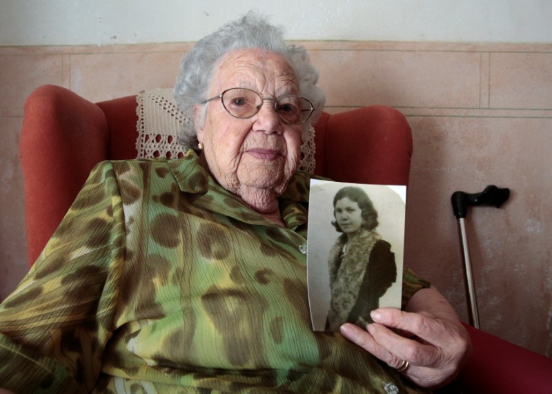 Rafaela Pons, 102, poses for a portrait with a picture of herself when she was young, in the living room of her home in Ferreries, on the Balearic island of Menorca, Spain, August 10, 2016. Pons lives alone although her daughter visits her daily. She is a devoted supporter of Real Madrid soccer club and takes a spoonful of honey every day. REUTERS/Andrea Comas