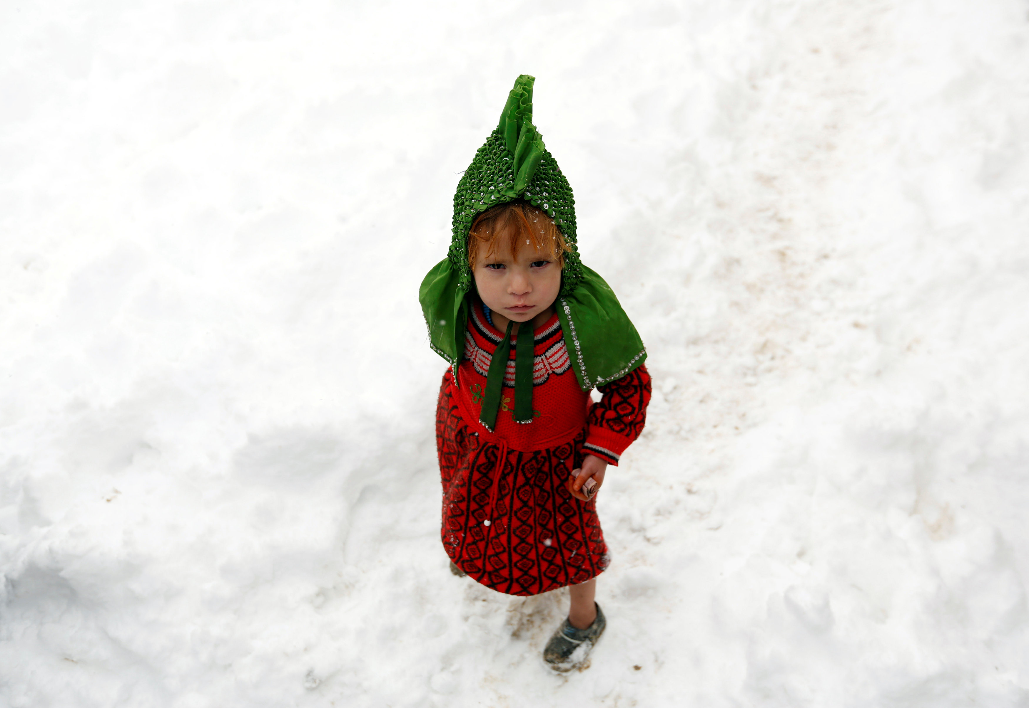 An Internally displaced Afghan child stands outside her shelter during a snowfall in Kabul, Afghanistan February  5, 2017. REUTERS/Mohammad Ismail