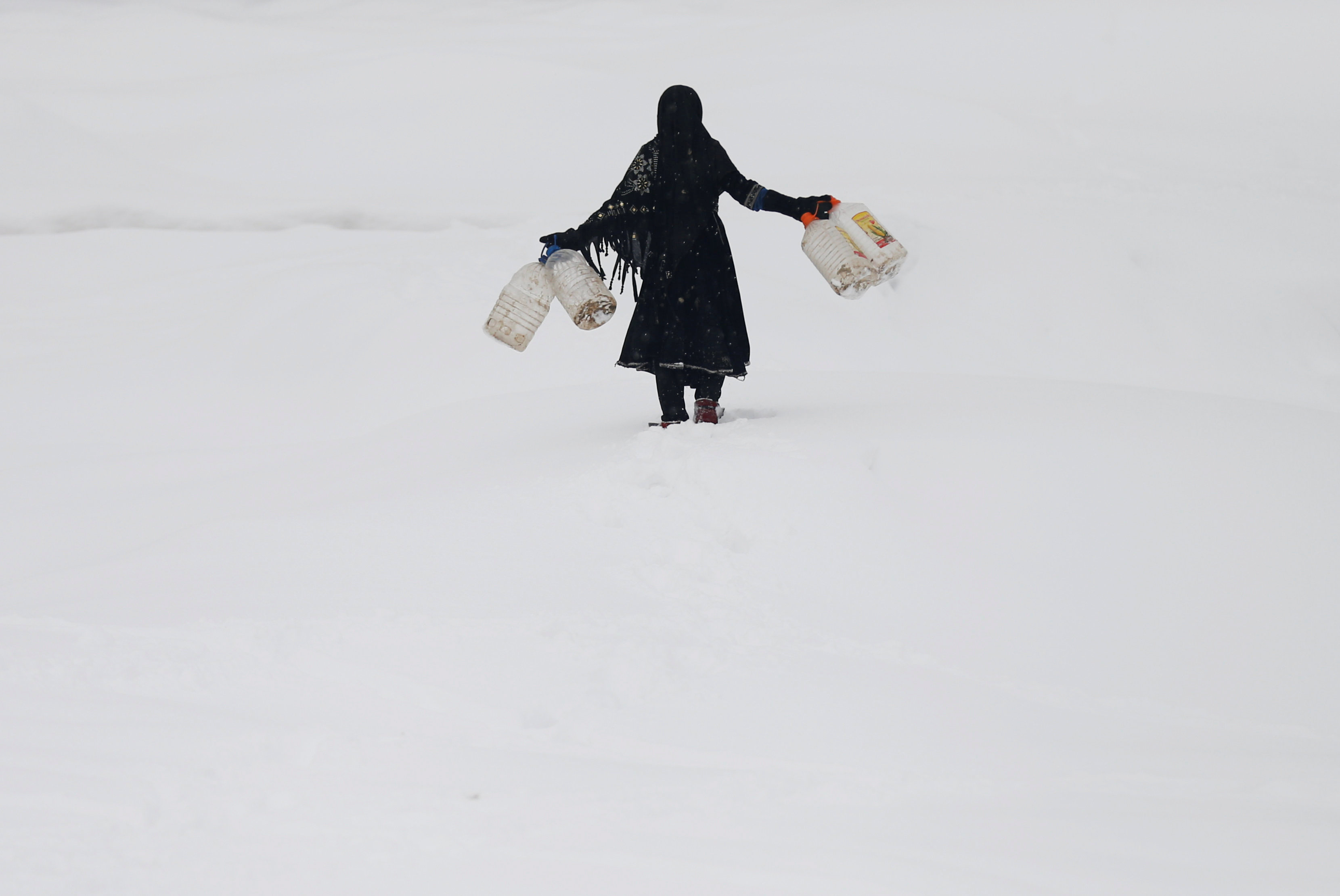 An Afghan girl carries empty water containers during a snowfall in Kabul, Afghanistan February  5, 2017. REUTERS/Mohammad Ismail