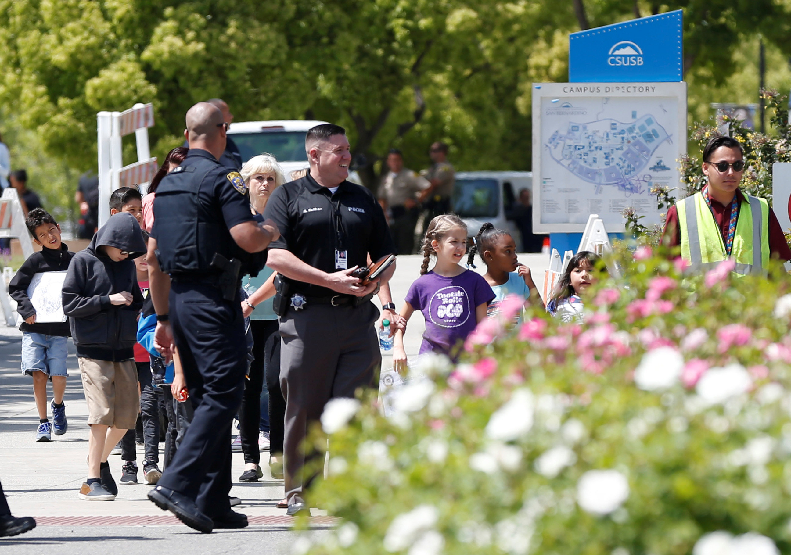 Police officers escort students from a campus of California State  University – San Bernadino, where they were evacuated after a shooting at  North Park Elementary School – EMTV Online