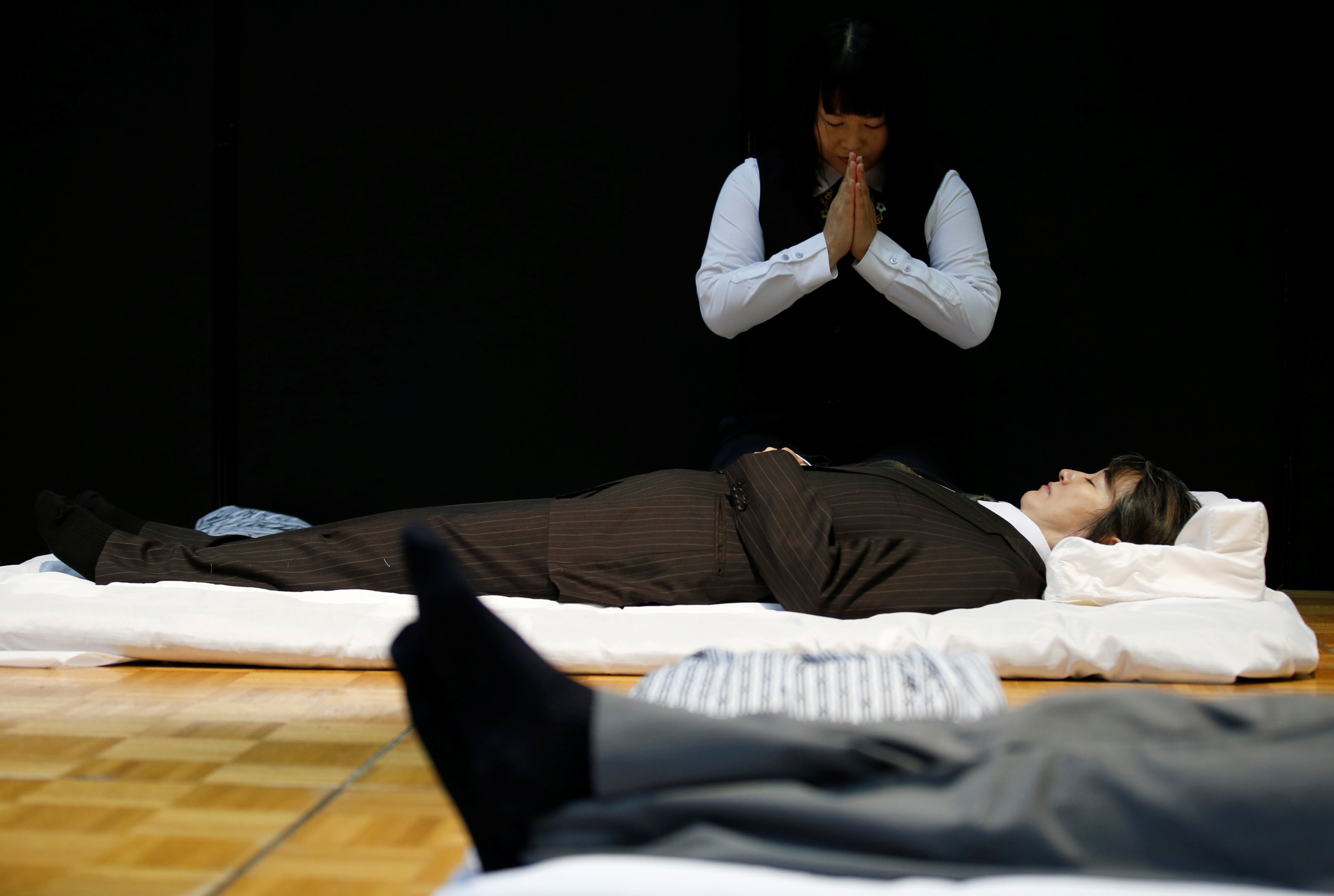 A funeral undertaker prays after dressing a model during an encoffinment competition at Life Ending Industry EXPO 2017 in Tokyo, Japan August 24, 2017 REUTERS/Kim Kyung-Hoon