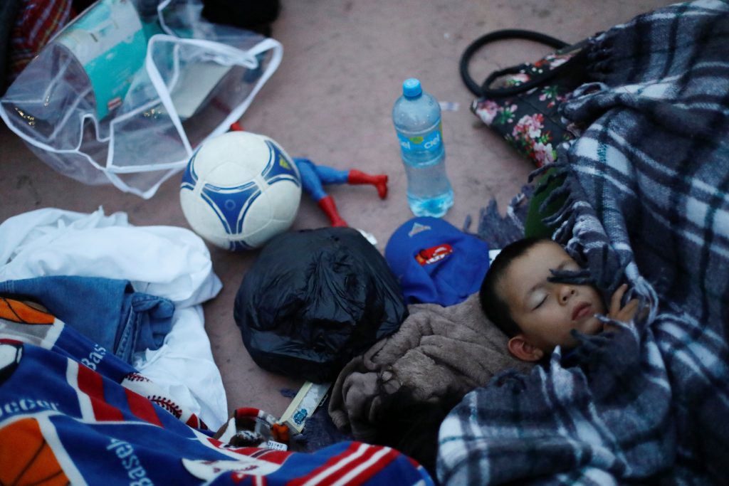 A child traveling with a caravan of migrants from Central America sleeps near the San Ysidro checkpoint after a small group of fellow migrants entered the United States border and customs facility, where they are expected to apply for asylum, in Tijuana, Mexico April 30, 2018. REUTERS/Edgard Garrido