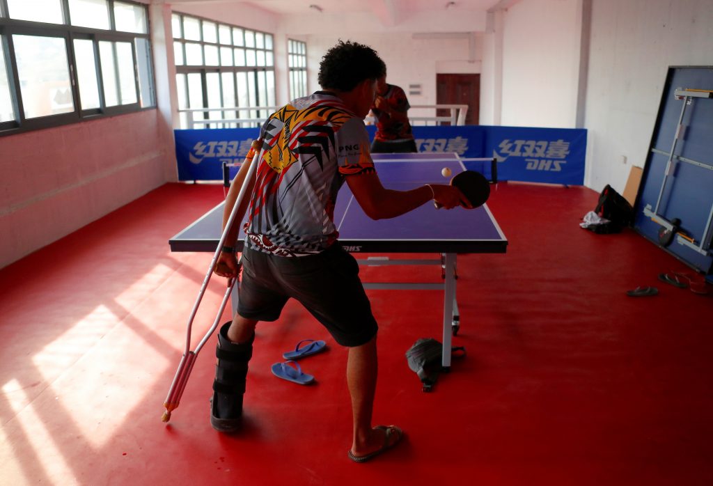 Injured Papua New Guinea table tennis player David Loi hits a ball as he practices with team mate Goada Elly at a Beijing-funded facility in central Port Moresby in Papua New Guinea, November 19, 2018. Picture taken November 19, 2018.   REUTERS/David Gray
